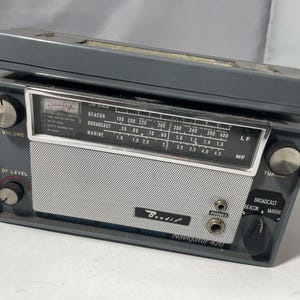 May include: A vintage grey Bendix Navigator 420 radio with a silver speaker cover. It has volume and tuning knobs, a frequency dial, and a headphone jack. The radio is rectangular with a matching grey top.