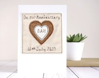 May include: A handmade anniversary card with a fabric heart design. The heart is brown with a white center, featuring the initials "D&H". The card reads "On our Anniversary 16th July 2023".