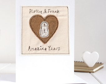 May include: A white card with a brown heart and the number 8 embroidered on it. The text "Holly & Frank Amazing Years" is also embroidered on the card.