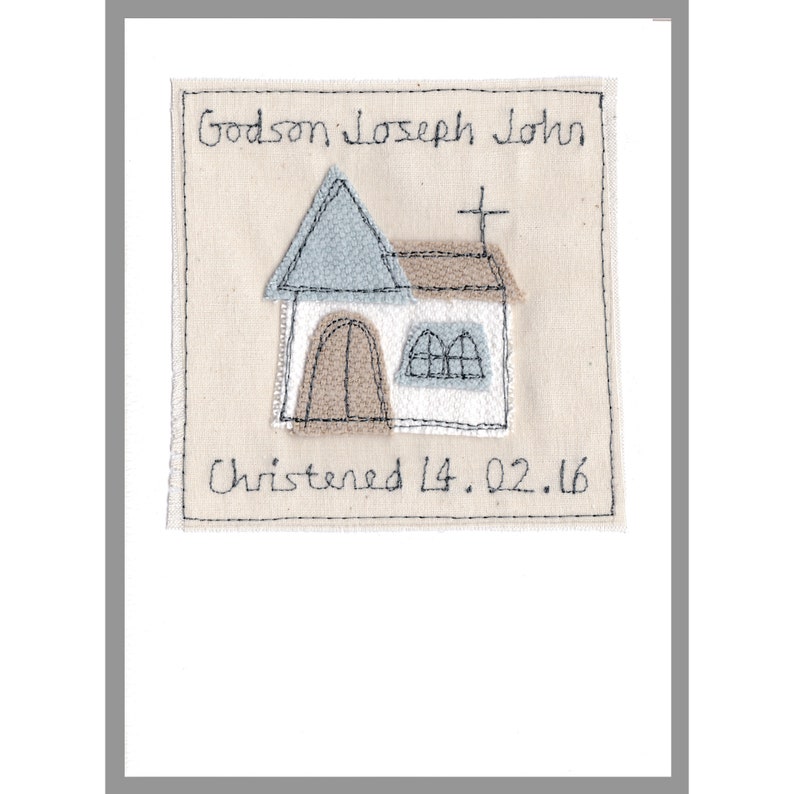 May include: A beige fabric square with a hand-stitched church design in blue, brown, and white. The text "Godson Joseph John" and "Christened 14.02.16" is stitched in black.