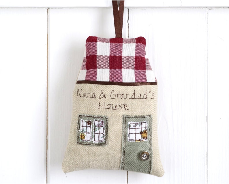 Personalised fabric hanging house decoration with a red gingham roof, embroidered with the words nana and grandads house