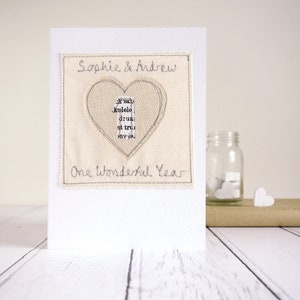 Personalisd 1st wedding anniversary card, embroidered with a beige heart a newspaper print number one and the couples names