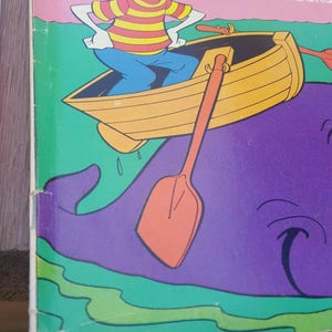 May include: A vintage comic book cover featuring Donald Duck as Moby Duck, rowing a boat on a purple whale. The cover is pink with green and white accents. The title reads "Moby Duck" and "The Last of the Luckles Ducks".