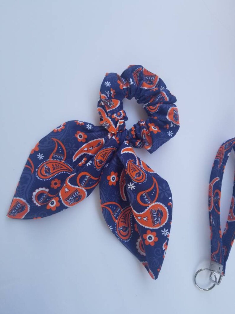 May include: A blue and orange paisley patterned hair scrunchie with a bow and a matching lanyard with a key ring.