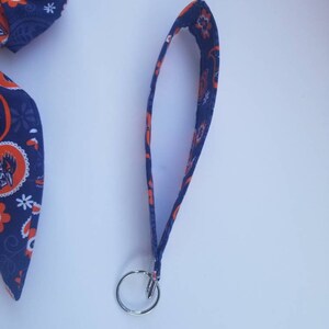 May include: A blue and orange fabric keychain with a silver key ring. The fabric has a paisley pattern.