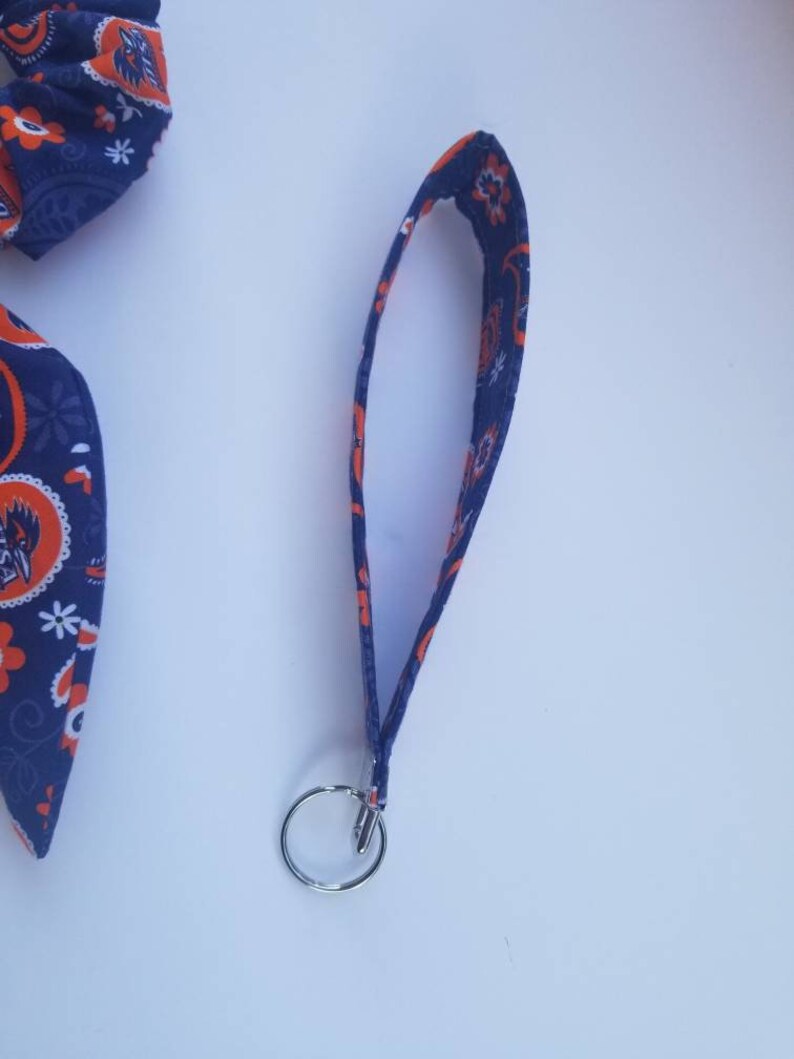 May include: A blue and orange fabric keychain with a silver key ring. The fabric has a paisley pattern.