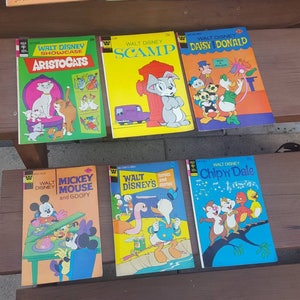 May include: A collection of nine vintage Walt Disney comic books featuring characters like Scamp, Daisy Duck, Donald Duck, Aristocats, Mickey Mouse, Goofy, and Chip 'n Dale. The comic books are in good condition and have colorful covers.