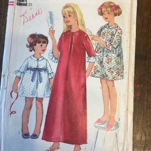 May include: Vintage Simplicity sewing pattern number 6814 for children's dresses. The pattern includes three dresses: a red long-sleeved dress, a blue and white polka dot dress, and a floral print dress. The pattern is for sizes 4, with a 23 inch bust.