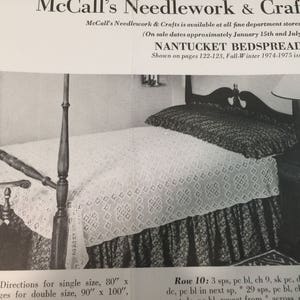 May include: A white crocheted bedspread on a wooden four-poster bed. The bedspread is made with a delicate lace pattern. The caption reads "Nantucket Bedspread" and "Shown on pages 122-123, Fall-Winter 1974-1975 issue".