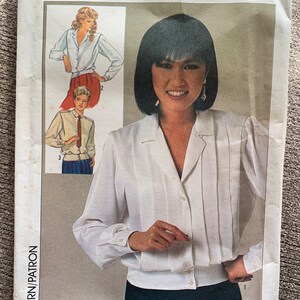 May include: Simplicity sewing pattern for a white blouse with a collar and long sleeves. The pattern includes instructions for sizes 10-38.