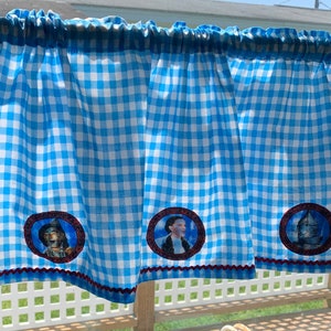 May include: Blue and white gingham valance with embroidered images of characters from the Wizard of Oz. The valance has a red trim and a scalloped edge.
