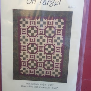 Puede incluir: Un patrón de acolchado para una colcha llamada "On Target" con un diseño a cuadros en marrón, blanco y burdeos. El patrón incluye instrucciones para una colcha de tamaño de regazo (155 cm por 201 cm) y una colcha de tamaño queen (246 cm por 269 cm).