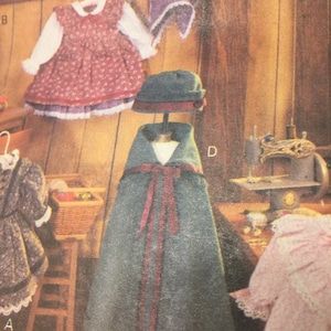May include: A vintage-style children's clothing set, including a red floral dress with white sleeves, a matching bonnet, and a green cape with a red bow. A hat and cape are displayed on a mannequin. A sewing machine is visible in the background.