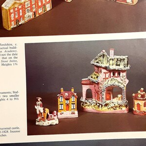 Może przedstawiać: Kolekcja miniaturowych domków ceramicznych, niektóre z dachami ze słomy, inne z misternymi detalami i kolorową farbą. Domki są ułożone na brązowej powierzchni.