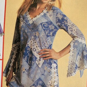 May include: A blue and white patterned tunic with a lace trim around the neckline and sleeves. The tunic has a V-neck and long sleeves.