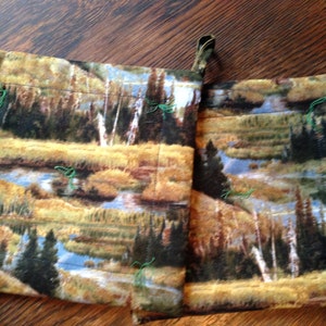 Puede incluir: Dos bolsas de tela marrón y verde con un estampado de escena de la naturaleza. Las bolsas tienen un cierre de cordón y están hechas de una tela suave y afelpada.