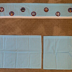May include: A set of three blue and white gingham fabric pillowcases. The pillowcases have a white lace trim. The top pillowcase has a row of embroidered images of characters from the Wizard of Oz.