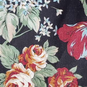 May include: Black fabric with a floral pattern featuring white, red, and orange roses, green leaves, and small blue flowers.