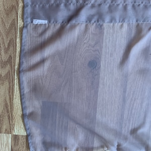 May include: A mauve sheer curtain panel with a scalloped edge and a small white tag that says "90".