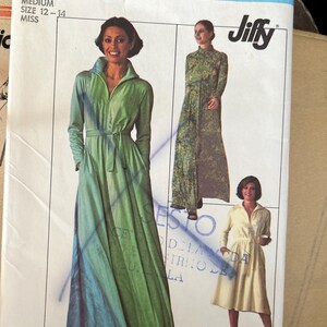 May include: A Simplicity 7833 Jiffy sewing pattern envelope for a medium size 12-14 miss dress. The cover features illustrations of three dress variations: a long-sleeved green maxi dress, a long-sleeved patterned maxi dress, and a short-sleeved dress.