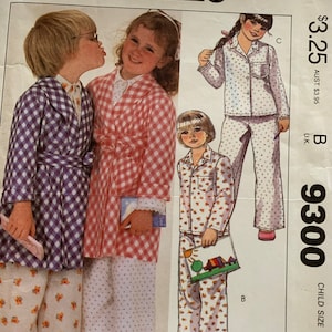 May include: A sewing pattern for children's pajamas. The pattern includes three different styles: a purple and white gingham robe, a pink and white gingham robe, and a floral print pajama set. The pattern is from McCall's and the pattern number is 9300.