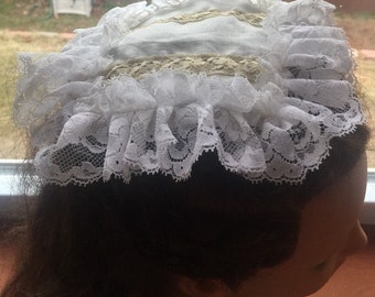 May include: White lace bonnet with a white fabric lining and a beige lace trim.