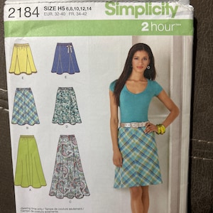 May include: A Simplicity sewing pattern envelope for model 2184, size H5. The packaging displays illustrations of six different skirt styles, including solid, plaid, and paisley patterns, alongside a photograph of a skirt in a blue and green plaid.