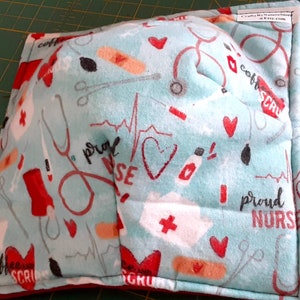 May include: A blue and red fabric square with a white background. The fabric has a pattern of medical symbols, hearts, and the words "proud nurse" and "coffee scrub".