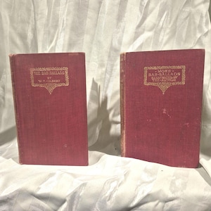 May include: Two vintage hardcover books with deep red cloth covers. The left book is titled The Bab Ballads by W.S. Gilbert. The right book is titled More Bab Ballads Illustrated by the Author. Both feature gold embossed text and decorative borders.