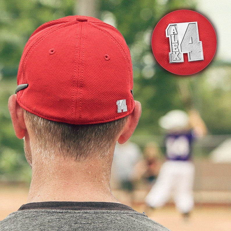 K&ouml;nnte beinhalten: Eine rote Baseballkappe mit einem silbernen Aufn&auml;her auf der R&uuml;ckseite, auf dem "Alex 14" steht.