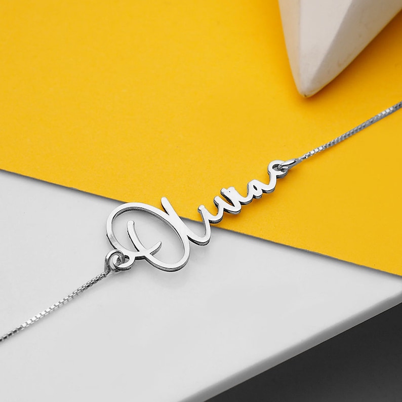 Peut inclure: Un collier en argent avec le nom "Olivia" &eacute;crit en cursive.