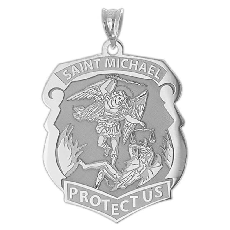K&ouml;nnte beinhalten: Silberner Anh&auml;nger mit einem Schild-Design, das den Heiligen Michael zeigt, wie er Satan besiegt. Auf dem Schild steht "Saint Michael Protect Us" geschrieben.