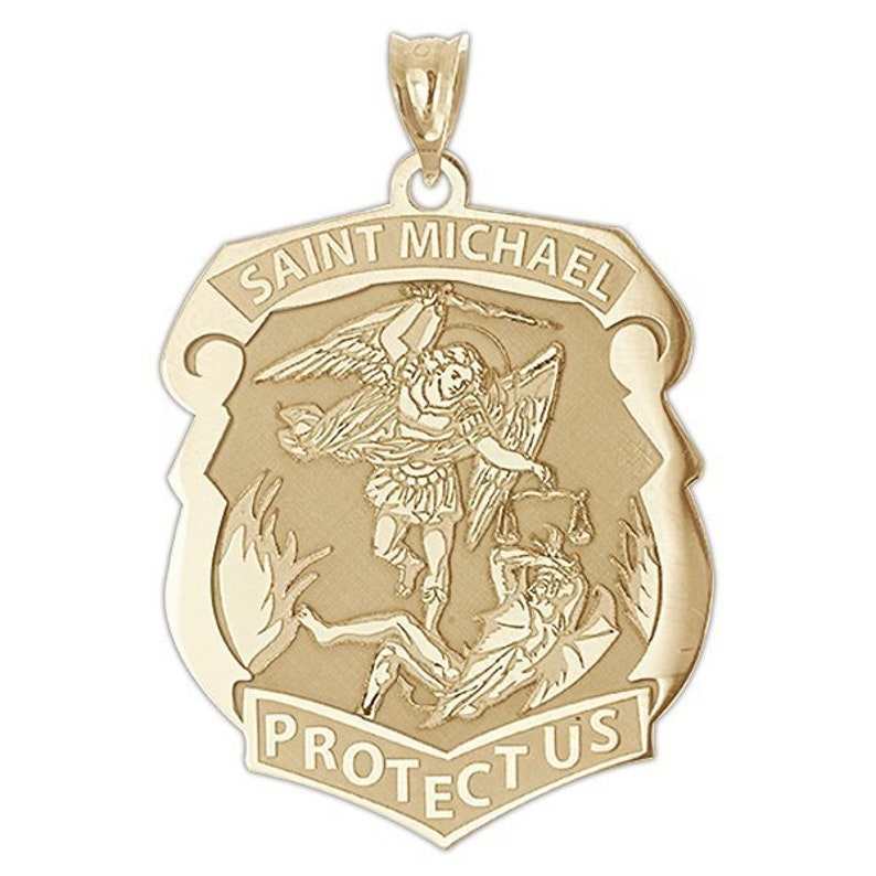 K&ouml;nnte beinhalten: Goldener Anh&auml;nger in Form eines Schildes mit den Worten "Saint Michael Protect Us" und einer Darstellung des Heiligen Michael im Kampf gegen einen D&auml;mon.