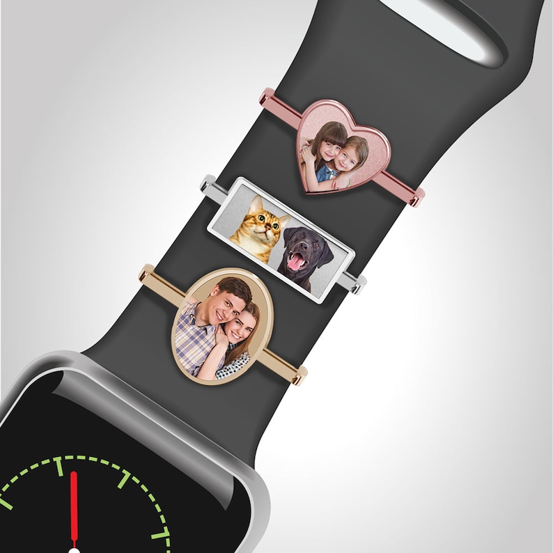 Pu&ograve; includere: Un Apple Watch nero con un cinturino nero. Il cinturino ha tre diversi accessori per foto: un accessorio a forma di cuore con una foto di due ragazze, un accessorio rettangolare con una foto di un gatto e un cane e un accessorio ovale con una foto di una coppia.