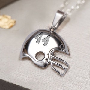 May include: Silver football helmet pendant necklace with the number 44 engraved on the front.