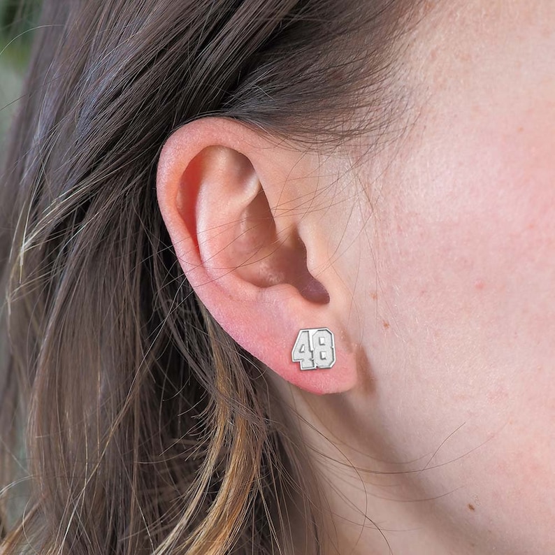 May include: Silver stud earrings with the number 48 in white lettering.