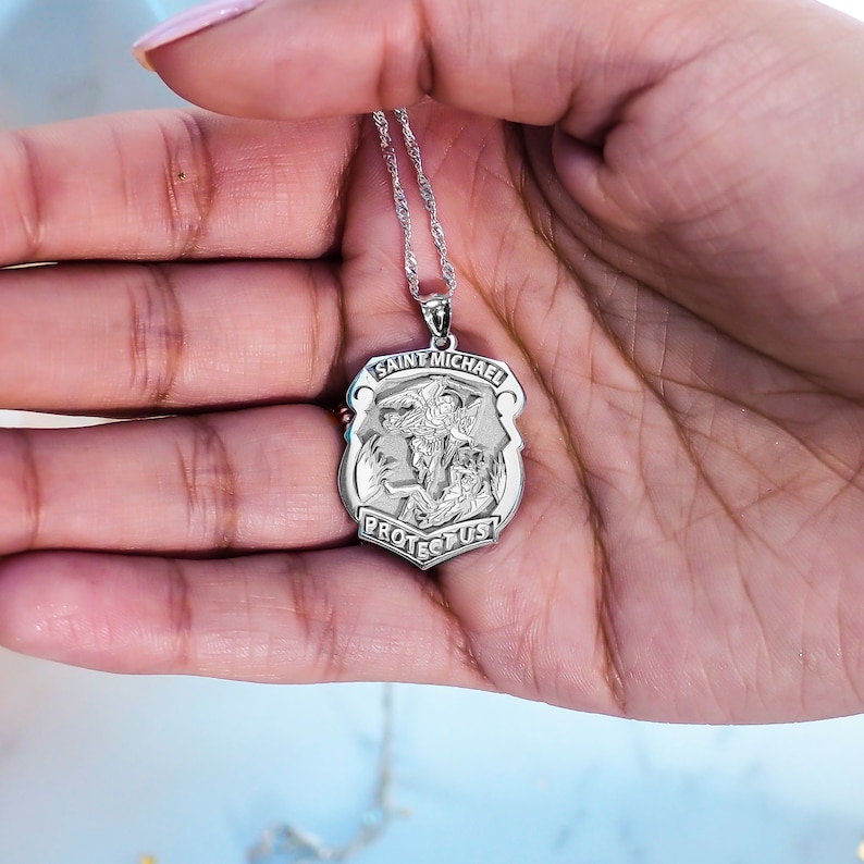 K&ouml;nnte beinhalten: Silberne Halskette mit Anh&auml;nger, der eine Medaille des Heiligen Michael, des Erzengels, mit den Worten "Heiliger Michael, sch&uuml;tze uns" zeigt.