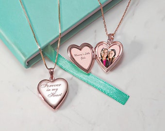 Puede incluir: Dos collares de oro con colgantes en forma de corazón. Un colgante contiene una foto de dos chicas y la inscripción "Mommy's Little Girls". El otro colgante tiene la inscripción "Forever in my Heart".