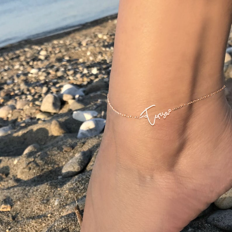 Peut inclure: Un d&eacute;licat bracelet de cheville en or avec le nom "Trista" &eacute;crit en cursive.