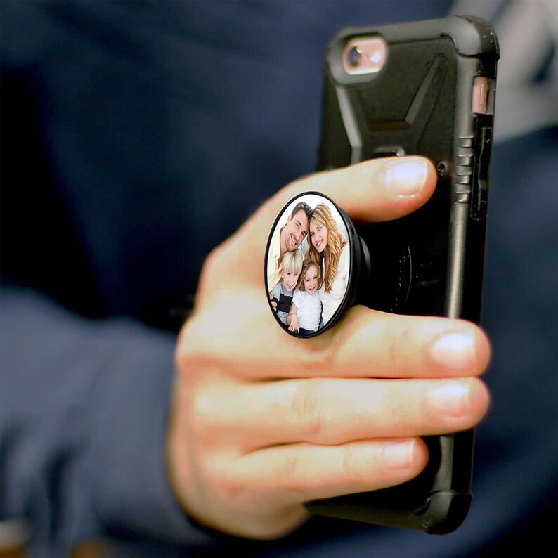 K&ouml;nnte beinhalten: Ein schwarzes Handy-Case mit einem PopSocket, das ein Foto einer vierk&ouml;pfigen Familie zeigt. Die Familie l&auml;chelt und wirkt gl&uuml;cklich. Der PopSocket ist ein runder, schwarzer Kreis mit wei&szlig;em Rand.