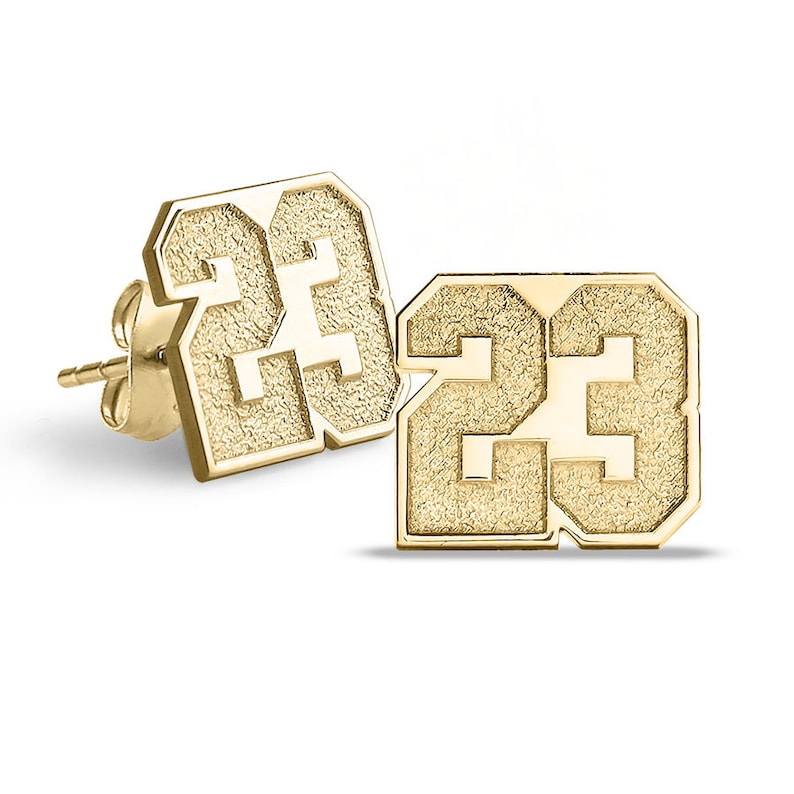 May include: A pair of gold-tone stud earrings featuring the number 23 in a bold, textured font.