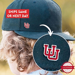 May include: A black baseball cap with a red and white University of Wyoming logo on the front. The logo is also on the back of the cap. The cap is officially licensed.