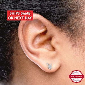 May include: Silver stud earrings featuring a small pointing hand design. The earrings are shown in a person's ear.