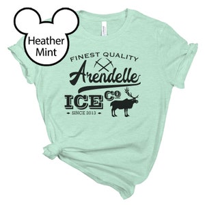 May include: A light green t-shirt with a black graphic design that says "Finest Quality Arendelle Ice Co. Since 2013". The graphic also includes a pair of crossed pickaxes and a reindeer.