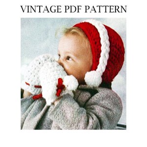 May include: A red and white crocheted baby hat with a white pom-pom on the end of the hat's brim. The hat has a white crocheted braid around the brim.