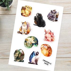 May include: A sheet of stickers featuring colorful illustrations of cats with crystals and gemstones. The stickers feature a variety of cat breeds, including a tabby cat, a Siamese cat, a Sphynx cat, and a black cat. The text "CRYSTALS CATS" is printed at the bottom of the sheet.