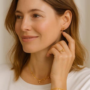 K&ouml;nnte beinhalten: Ein Goldschmuckset bestehend aus einer zarten Kettenhalskette mit kleinen runden Perlen, einem Ring mit einer Ansammlung winziger Goldkugeln und passenden Ohrsteckern, die jeweils mit einer kleinen Gruppe von Goldperlen gestaltet sind.