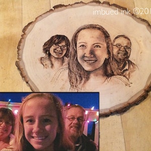 Op de afbeelding: Een houten schijf met een gebrandschilderd portret van drie personen. Het portret is in zwart-wit en toont een vrouw met lang haar, een vrouw met kort haar en een man met een baard. De houten schijf ligt op een houten oppervlak. De tekst "imbued ink &copy;2016" staat in de rechterbovenhoek van de afbeelding.