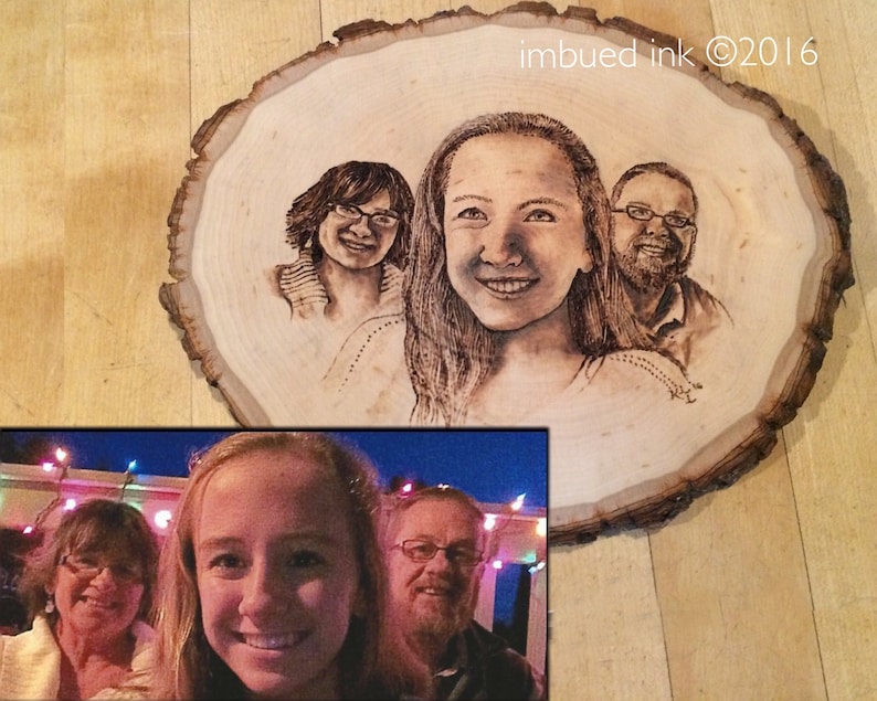 Op de afbeelding: Een houten schijf met een gebrandschilderd portret van drie personen. Het portret is in zwart-wit en toont een vrouw met lang haar, een vrouw met kort haar en een man met een baard. De houten schijf ligt op een houten oppervlak. De tekst "imbued ink &copy;2016" staat in de rechterbovenhoek van de afbeelding.