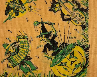 May include: A vintage Halloween-themed illustration featuring a witch playing a pumpkin drum, a scarecrow playing an accordion, a black cat playing a cello, and a bird playing a trumpet. The illustration is in shades of green, black, and yellow on a beige background.